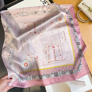 Carré de soie rose élégant avec motifs de mors et de chaînes sur un bureau en bois