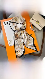 Détail d'un foulard en soie fleurie de 15x150cm noué sur un support orange
