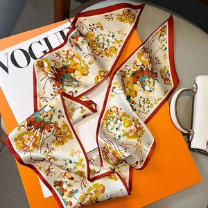 Détail d'un foulard en soie aux fleurs orange vif et bordures rouge foncé élégantes