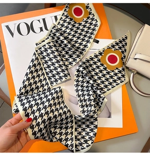 Close-up of houndstooth silk scarf with floral details on a fashion magazine and gift box