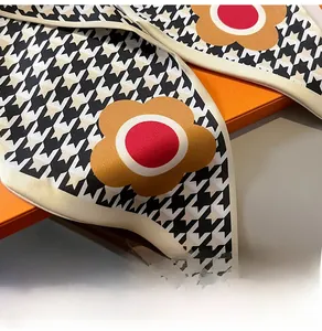 Close-up of silk scarf with houndstooth and floral pattern on orange gift box