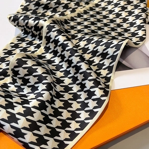 Macro detail of houndstooth silk scarf texture with elegant orange gift packaging boxes