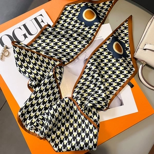 Detail of houndstooth twilly silk scarf styled with magazine and luxury gift box
