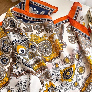 Detail of a silk scarf with orange and navy paisley patterns and soft fabric texture