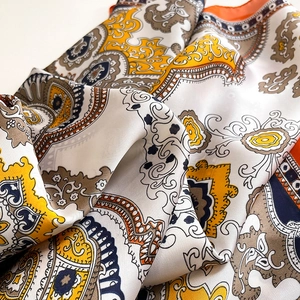 Elegant paisley floral satin silk scarf with orange and gold patterns in soft wavy folds