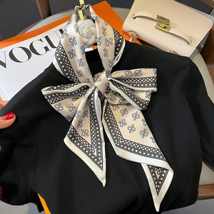 Elegant white skinny silk scarf with black paisley pattern tied as a bow with camellia brooch
