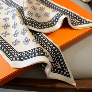 Detail of silk-feel scarf with paisley print and geometric border on orange box