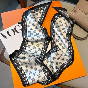Detail of silk narrow scarf with paisley print on luxury box and leather bag