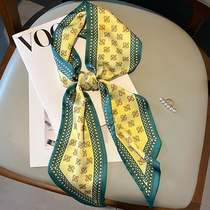 Elegant yellow and green silk twilly scarf with knot patterns on a VOGUE magazine