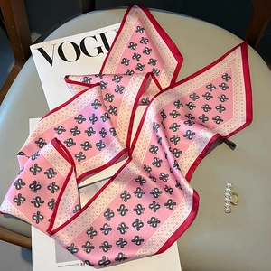 Detailed view of pink paisley silk scarf with red stitched edges and soft satin texture