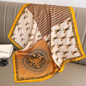Vintage horse print satin square scarf in yellow and beige on a grey leather sofa