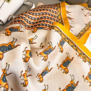 Close-up of silk scarf with orange horse pattern and elegant geometric borders on white bag