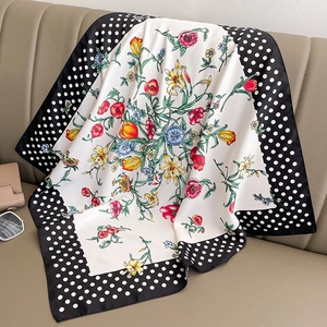 Polka dot and floral silk scarf styled on a leather chair with elegant accessories