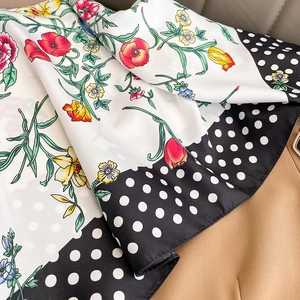 Detailed macro view of colorful floral silk scarf with black polka dot edge