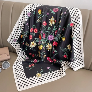 Hepburn style silk scarf with polka dots and colorful floral print on leather sofa