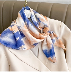 Detail of artistic blue and orange gradient silk square scarf tied on a beige suit lapel
