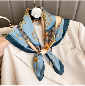 Dettaglio di foulard in seta con catene barocche su un blazer con spilla a camelia