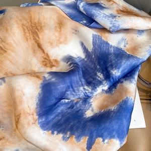Close-up of elegant gradient silk scarf with blue and brown ink pattern texture