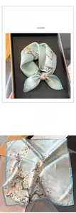 Détail d'un carré de soie avec imprimé magnolia vintage dans un coffret cadeau chic
