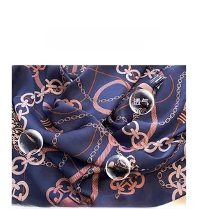 Detail of navy blue silk-like scarf featuring pink chain pattern and glossy texture
