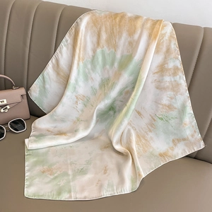 Detail of silk scarf with green gradient pattern draped on beige leather background