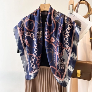 Navy blue silk scarf with pink chain pattern and tassels on a wooden hanger