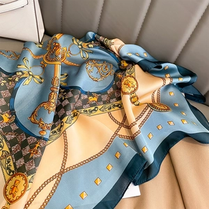 Dettaglio di un foulard in seta vintage con catene dorate e motivi a cintura su raso