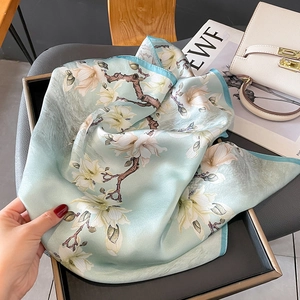 Élégant foulard en soie à imprimé magnolia vert clair sur un sac à main blanc chic