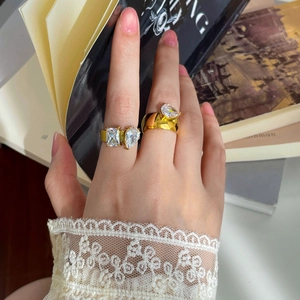 Close-up of 18K gold plated rings with teardrop and square zircon stones on fingers