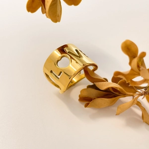 Macro detail of 18K gold-plated wide band ring featuring hollow LOVE and heart design
