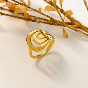 Detail of multi-layer curved golden ring with abstract vortex design and metal texture