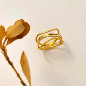 Macro detail of multi-layer wavy hollow gold ring with polished finish on white base