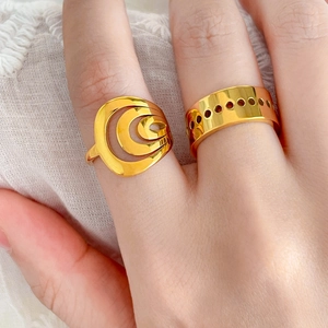 Polished 18K gold layered spiral and perforated hollow rings on white fabric