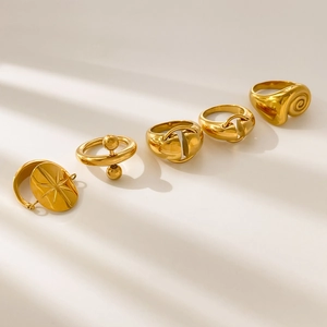 Five 18K gold plated stainless steel rings featuring star and spiral designs on beige surface