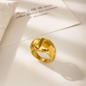 Macro view of a chunky gold dome ring with a horizontal bar detail on a white pillow