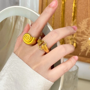 Close-up of 18K gold plated horsebit and snail spiral rings worn on a hand