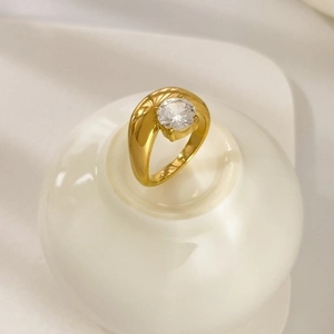 Vista macro di anello placcato oro 18K con zircone rotondo su supporto in ceramica bianca