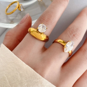 Dettaglio degli anelli in titanio placcato oro 18K con zirconi rotondi e a taglio marquise