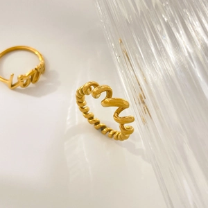 Nahaufnahme von goldenem Spiraldrehring und Love-Schriftzug-Ring auf weißem Hintergrund