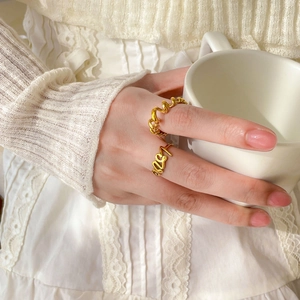 Goldene Titanstahlringe mit Love-Schriftzug und Kettendesign an der Hand einer Frau