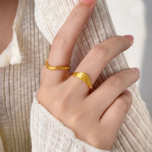 Makroaufnahme von Sonnenstrahl- und Wellenringen aus Gold am Finger eines Models