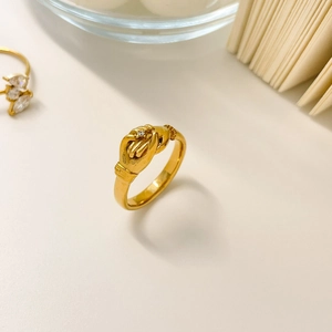 Macro detail of 18K gold plated titanium ring with hands holding design and small zircon