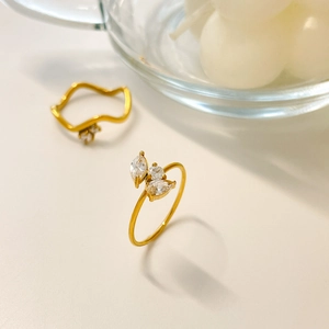 Detailed view of wave band and zircon rings in 18K gold plated stainless steel