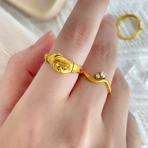 Detail of 18K gold plated titanium ring with hands clasping design and white zircon accents