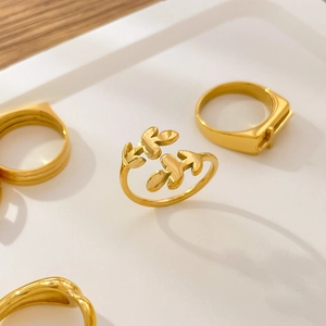 Polished 18K gold-plated titanium steel leaf ring and geometric jewelry on white tray