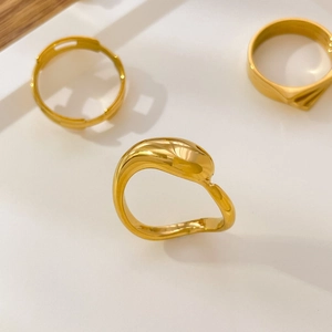 Close-up of triple-layered curved gold rings with liquid metal and organic hollow leaf design