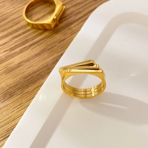 Detail of 18K gold-plated titanium rings with layered geometric bars and leaf motif