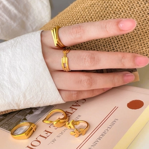 Detailed close-up of 18K gold plated stackable rings featuring cross and leaf motifs