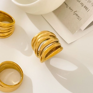 Polished 18K gold-plated multi-layer crossover ring displayed in a lifestyle setting