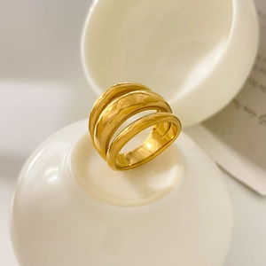 Close-up of multi-layer 18K gold plated curved ring on a white ceramic display